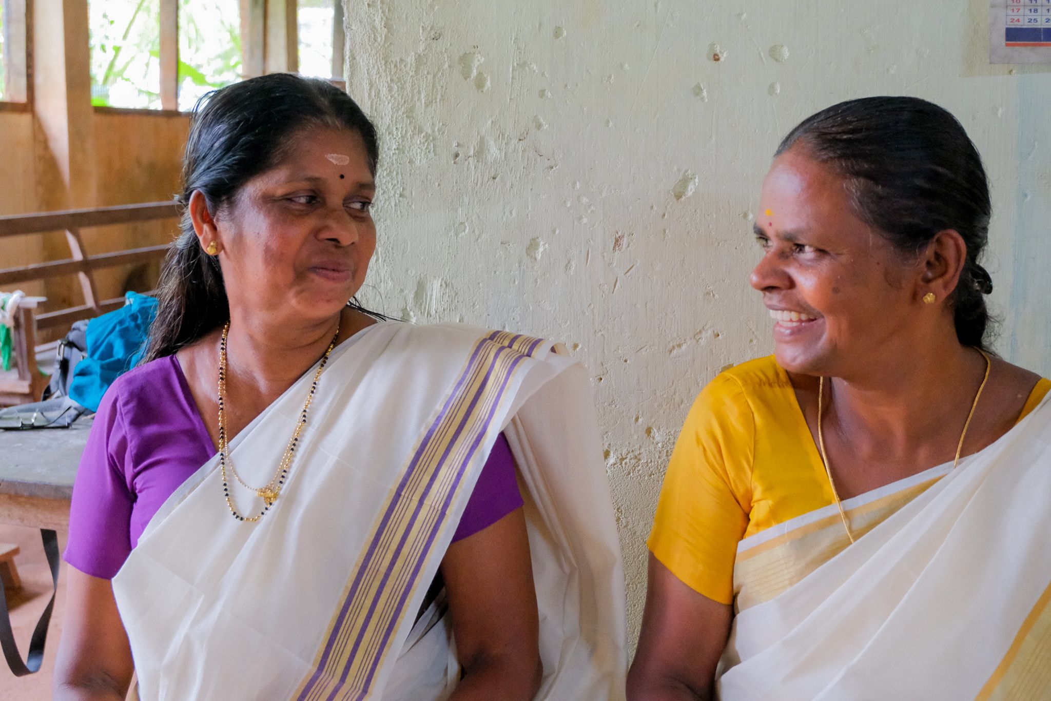 Two weavers laughing together in the society's workroom