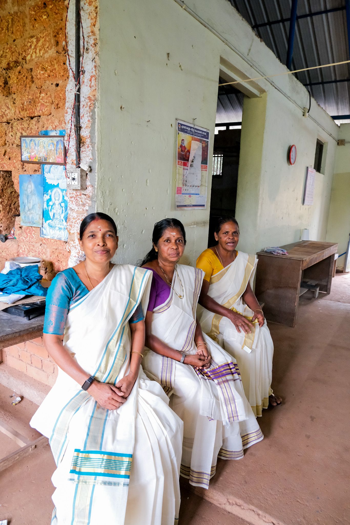 Ammini, Kumari and Sheeja seated in the weaving shed in their Kasavu sarees