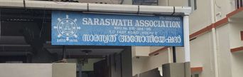 A blue signboard reading ‘Saraswath Association, T.D. East Road, Kochi-2, Estd. 1938’ mounted on a building’s covered entrance.