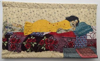 A quilted fabric panel showing a woman in a yellow dress lying asleep on layered cloth, the bedding pieced from rose-printed and patterned scraps.