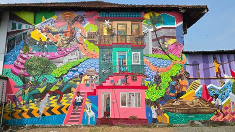 Large colorful wall mural depicting local figures, boats and a house