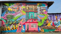 Large colorful wall mural depicting local figures, boats and a house