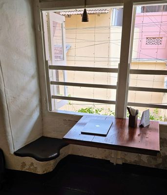 Window-side seating nook with a curved built-in bench and a small table holding a closed laptop.