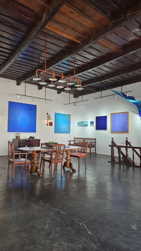 Gallery interior with blue abstract paintings and a wooden dining table