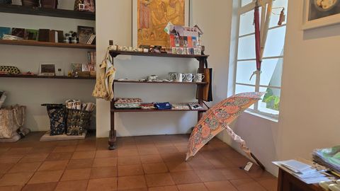Shop interior with shelves of ceramics and textiles, an open umbrella on the floor