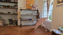 Shop interior with shelves of ceramics and textiles, an open umbrella on the floor