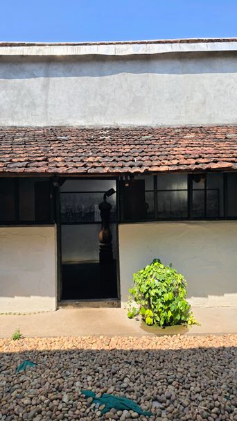 Old building doorway with a carved wooden pillar, pebbled courtyard
