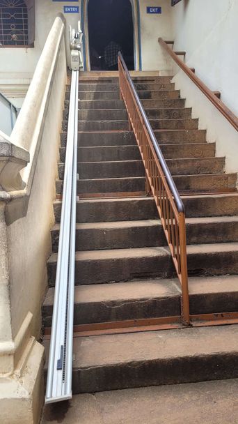 Stone staircase with a rail-mounted stairlift, leading to doors marked 'Entry' and 'Exit'