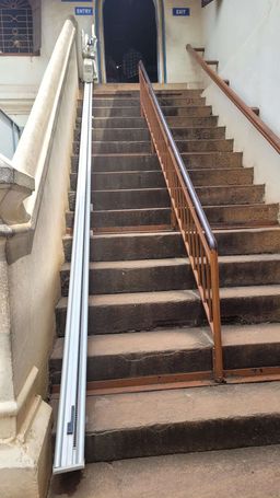 Stone staircase with a rail-mounted stairlift, leading to doors marked ‘Entry’ and ‘Exit’