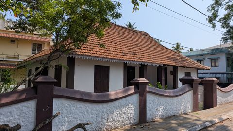 Traditional tiled-roof house behind a red and white boundary wall
