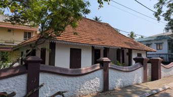 Traditional tiled-roof house behind a red and white boundary wall
