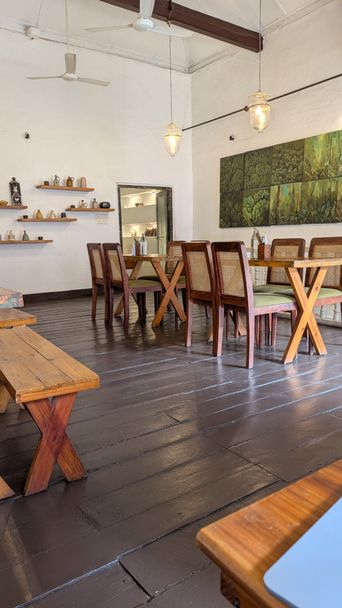 Cafe interior with wooden cross-frame tables, chairs and hanging lanterns