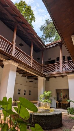 Heritage building courtyard with a wooden upper balcony and a stone well or planter