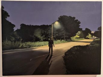 A dark painting at Muziris Contemporary of a lone figure standing under a streetlight on a road at night.