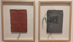 Two framed pieces of textured handmade paper artwork stitched with coloured thread, hanging on a white gallery wall at Muziris Contemporary.
