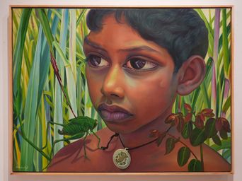 A painting at Muziris Contemporary of a boy among tall green leaves with a grasshopper perched on his shoulder.