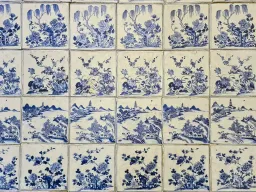 Rows of blue-and-white Chinese porcelain tiles, each hand-painted with a different floral or landscape scene, covering the synagogue floor.
