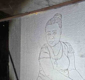 A line drawing of a woman with an upswept hairstyle, incised directly into a rough plastered wall.