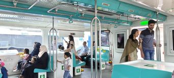 Interior of a Kochi Water Metro passenger cabin with teal seats and standing passengers.