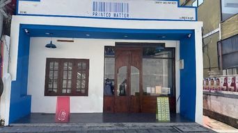 Blue and white shopfront with a barcode-style sign reading ‘Printed Matter’.