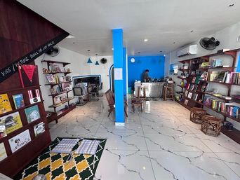 Bookshop interior with a chalkboard sign reading ‘Kids/Picture Books for Lost Adults’ and wooden shelves.
