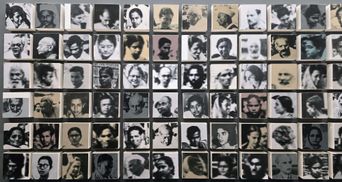 A grid of dozens of small black-and-white portrait photographs mounted on blocks, each showing a different face.