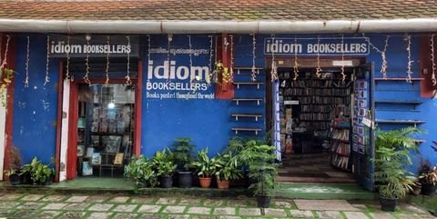 Blue shopfront with ‘Idiom Booksellers’ signage and potted plants outside.