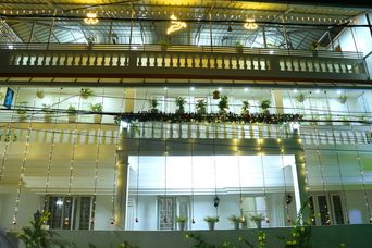 Night view of a cream multi-storey building with balconies strung with fairy lights and potted plants along the railings.