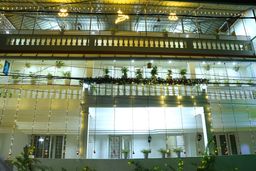 Night view of a cream multi-storey building with balconies strung with fairy lights and potted plants along the railings.