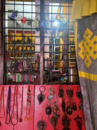 Curio shop window display of bead necklaces, brass padlocks and small Buddha statuettes